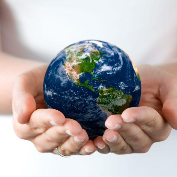 A person holds a small globe in their hands, with North and South America visible on the globe.