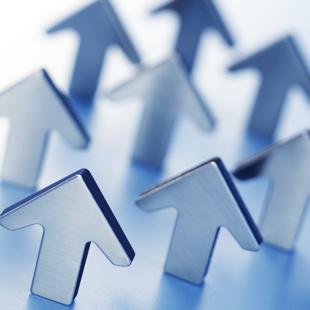 Multiple metallic arrows pointing upward on a blue surface, symbolizing growth or progress.