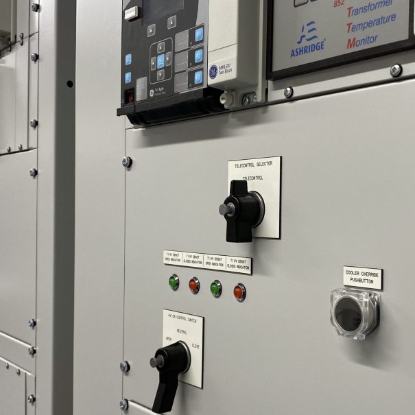Close-up view of an industrial control panel with labeled switches, buttons, indicator lights, and digital monitoring displays.