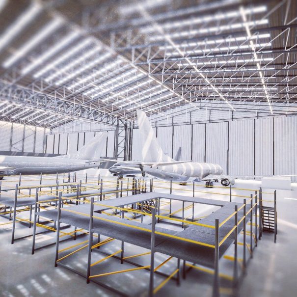 Large aircraft inside a spacious, well-lit hangar with metal scaffolding and maintenance platforms in the foreground.